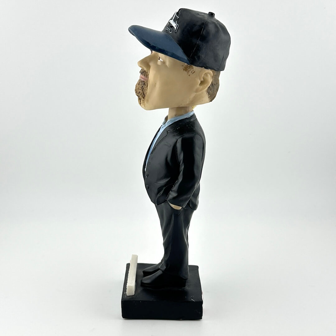 Bobblehead figure of a man in a suit and cap on a white background