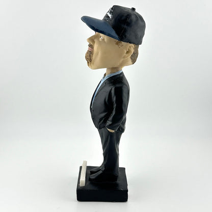 Bobblehead figure of a man in a suit and cap on a white background