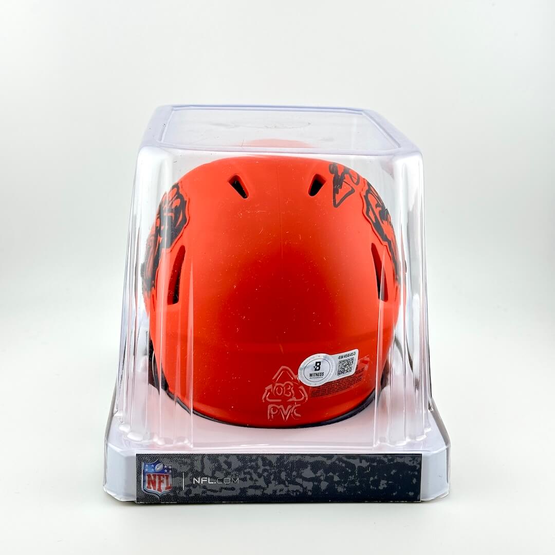 Orange helmet with black designs in a clear display case on a white background