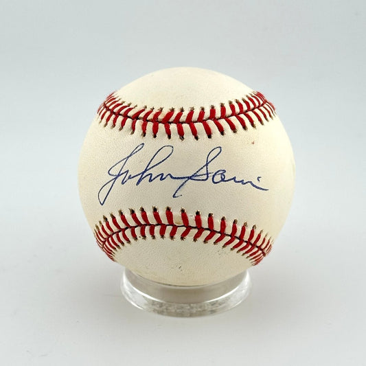 Baseball with autograph on a clear stand against a light gray background