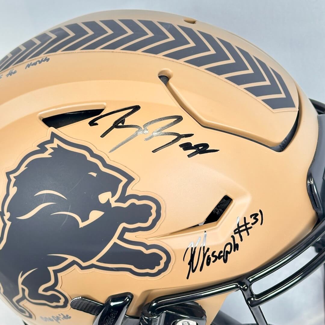 Beige football helmet with black lion logo and signatures on a light gray background