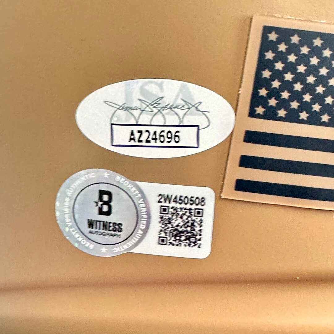 Two stickers on a beige surface, one with a signature and number, the other with a QR code and branding.