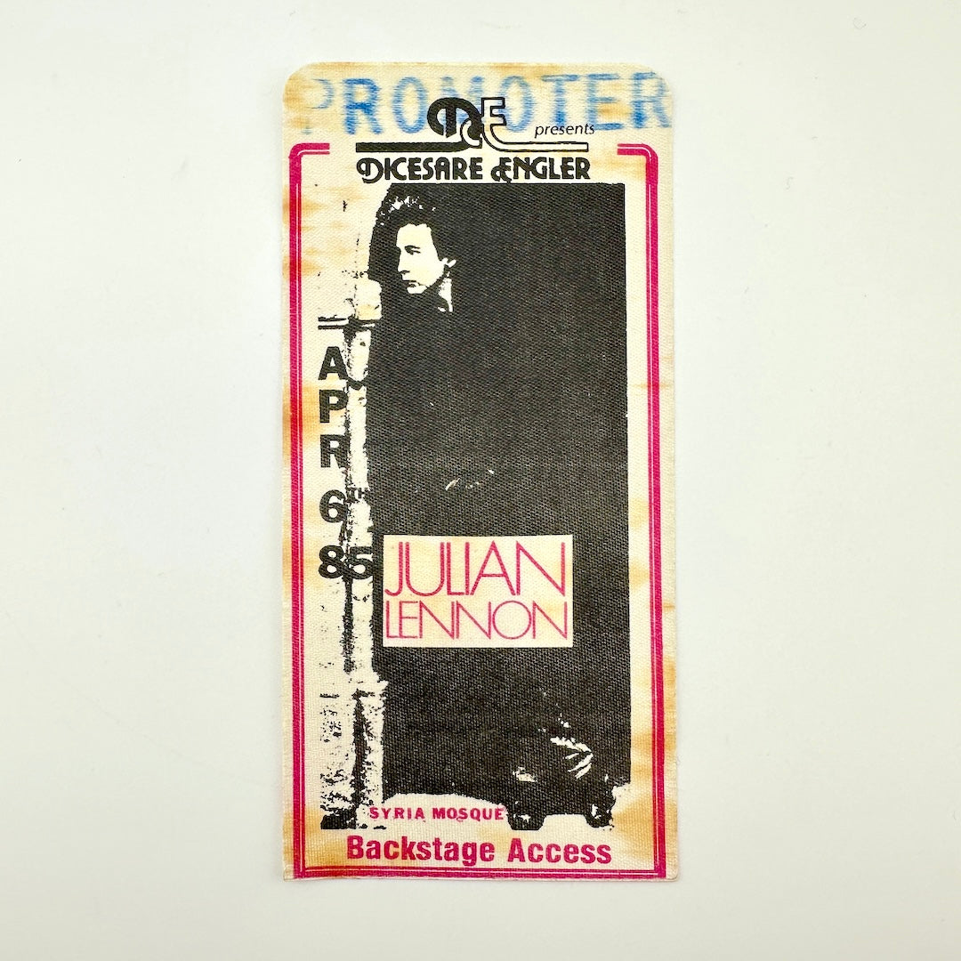 Backstage pass with black and white image of artist and event details in black text. 