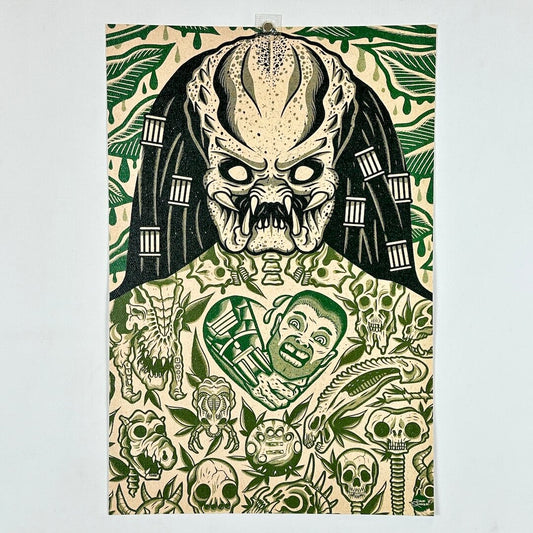 Art print featuring a stylized green and black illustration of a Predator-like creature with skulls, foliage, and surreal faces.