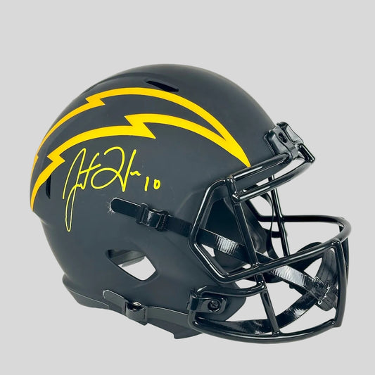 A matte black Los Angeles Chargers football helmet with a yellow lightning bolt graphic, signed in yellow marker.