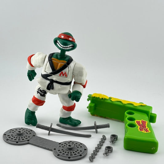Anthropomorphized turtle in red mask wearing white karate uniform. Pictured with movement gun & grey accessories.