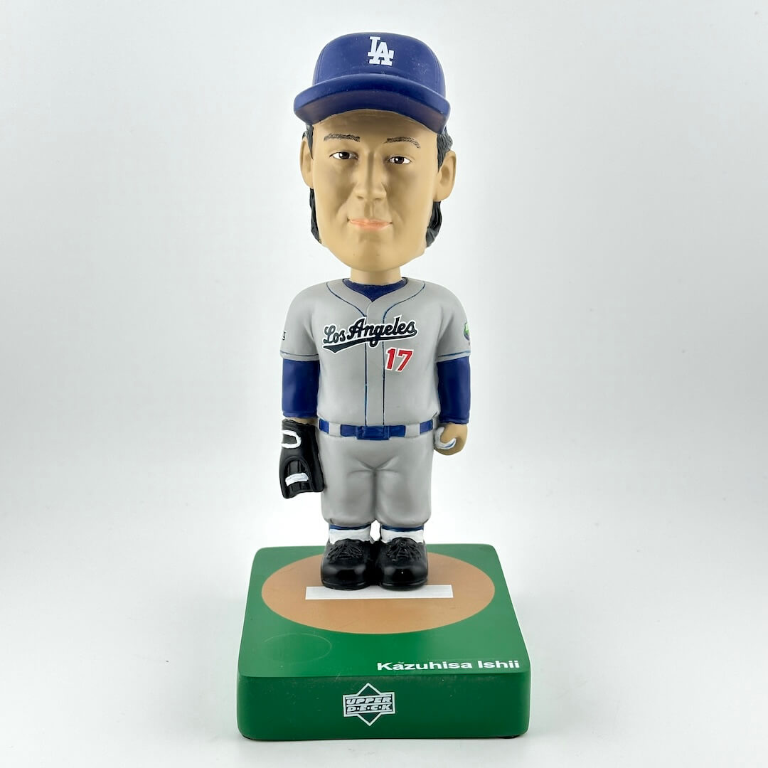 Bobblehead figure of a baseball player in a gray and blue uniform with a cap, on a white background.
