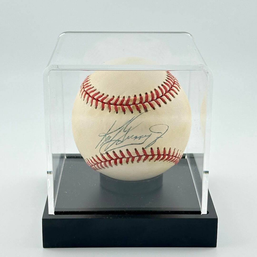 Autographed baseball in plastic cube with black base. 