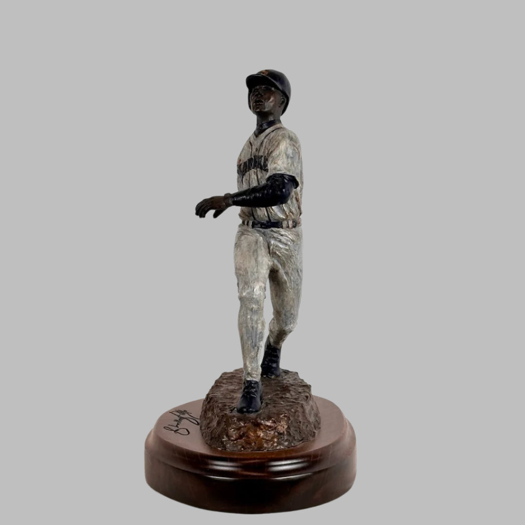 Frontal view of Ken Griffey Jr. bronze statue of him posed at the end of a swing, his signature etched into wooden base.