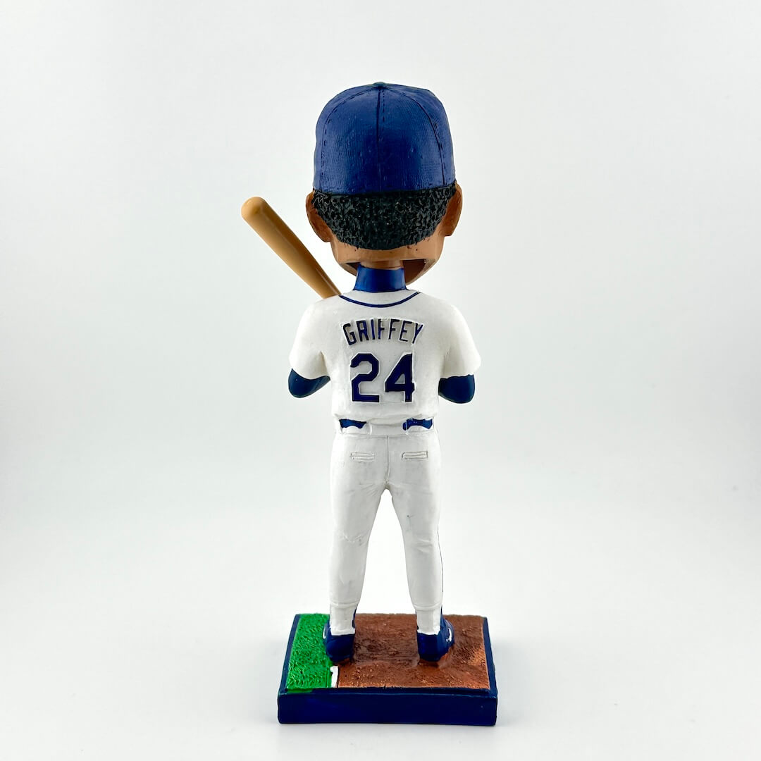 Bobblehead figure of a baseball player in a white uniform with blue accents, holding a bat on a white background.