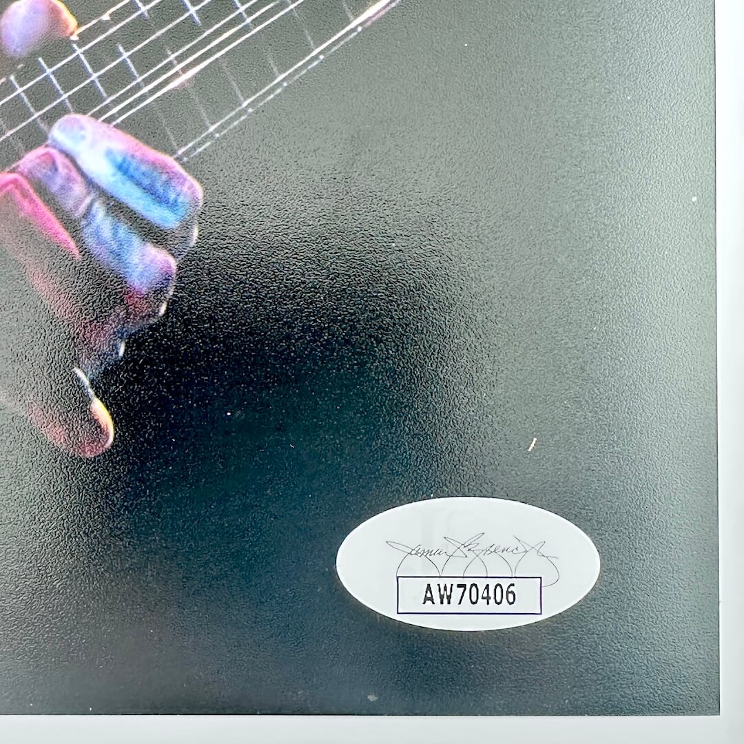 Close-up of a guitar with a hand on the neck, featuring a brand label with a serial number.