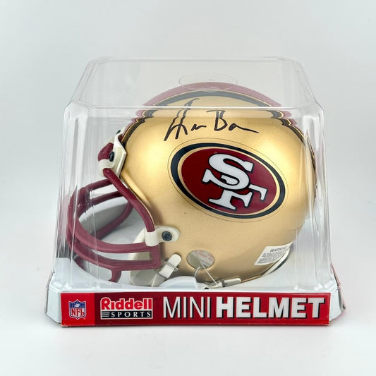 Gold Riddell mini football helmet with 49ers logo and signature in clear packaging on white background. 