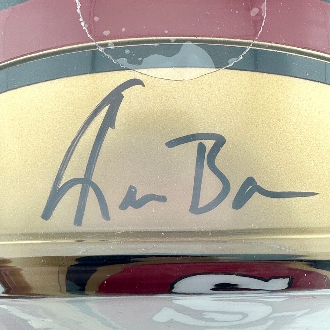 Gold helmet with a signature on a colorful background