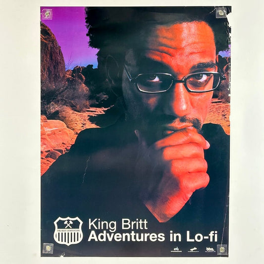 Poster of man with hand on chin with red rocks in background. 