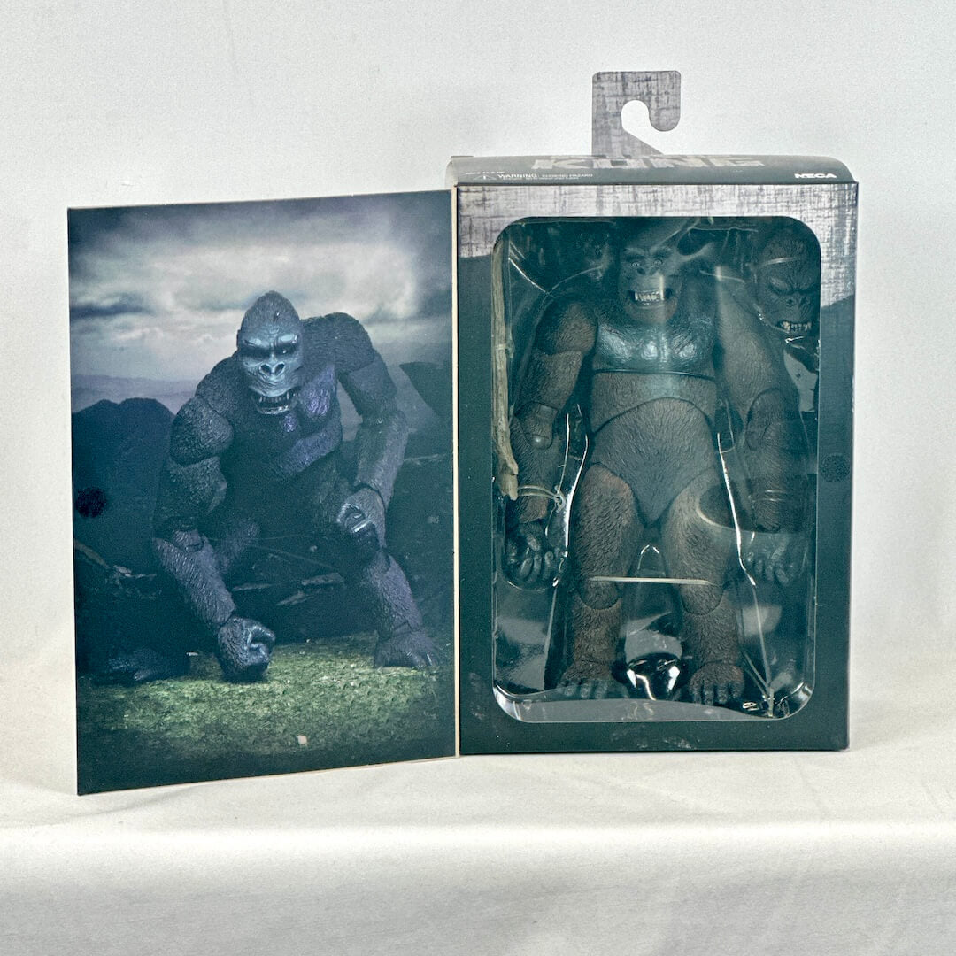 Toy figure of a gorilla in packaging with a black and white photo of a similar figure on a white background