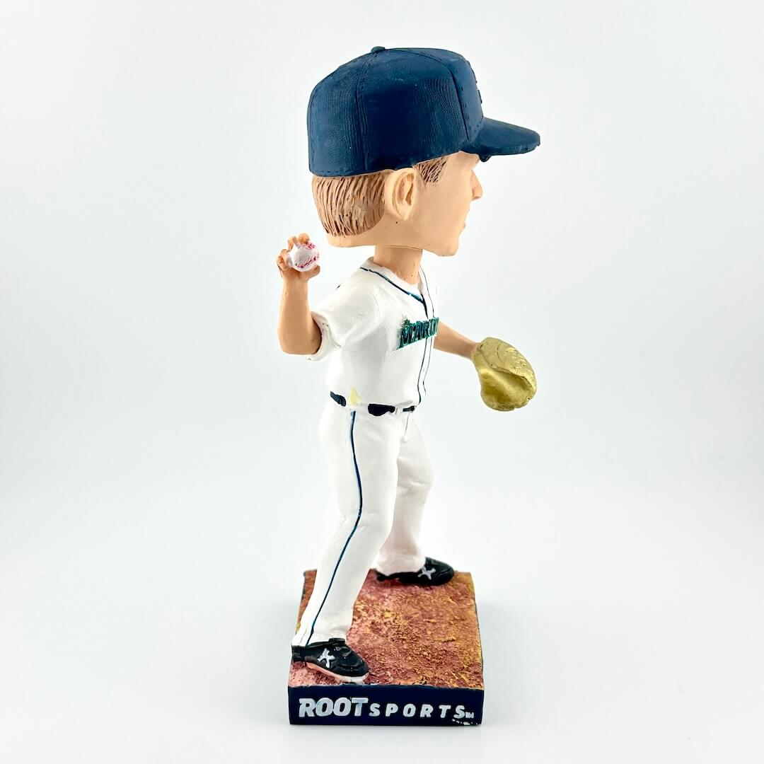 Baseball player bobblehead figure with a white uniform and navy cap, holding a baseball and glove, on a white background.