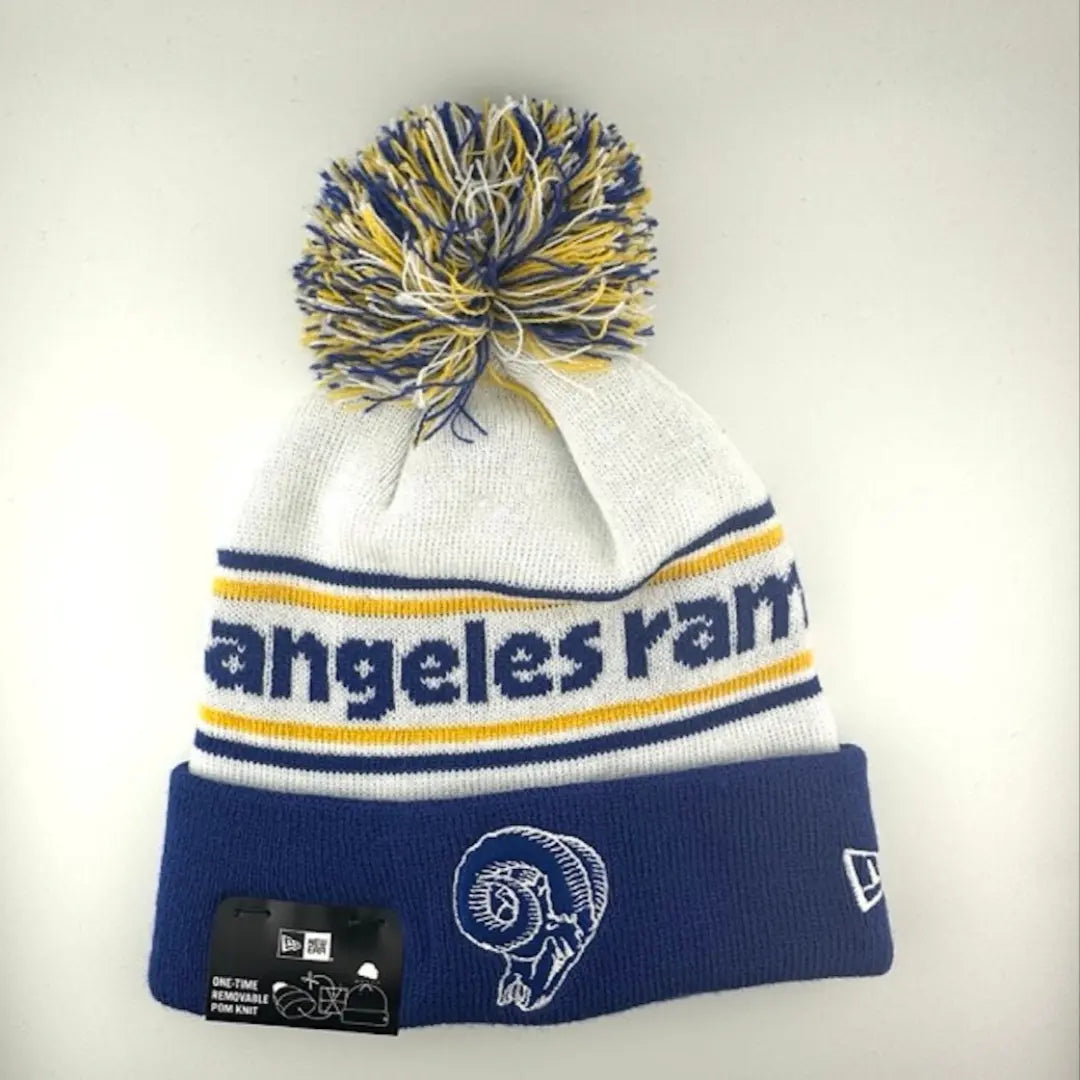 White knit cap with yellow/blue stripes around blue team name, Rams logo in center of blue cuff & yellow/blue/white pom atop