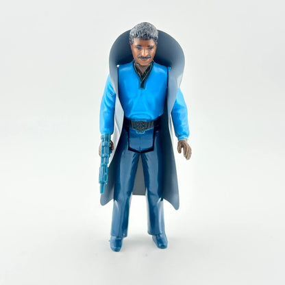 Action figure in blue outfit with cape and weapon on white background. 