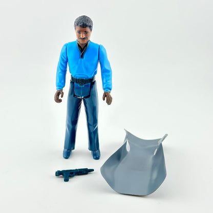 Action figure in blue outfit with cape and weapon on white background. 
