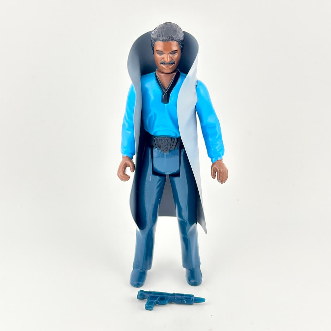 Action figure wearing a blue robe and dark pants, with a blue weapon on white background. 