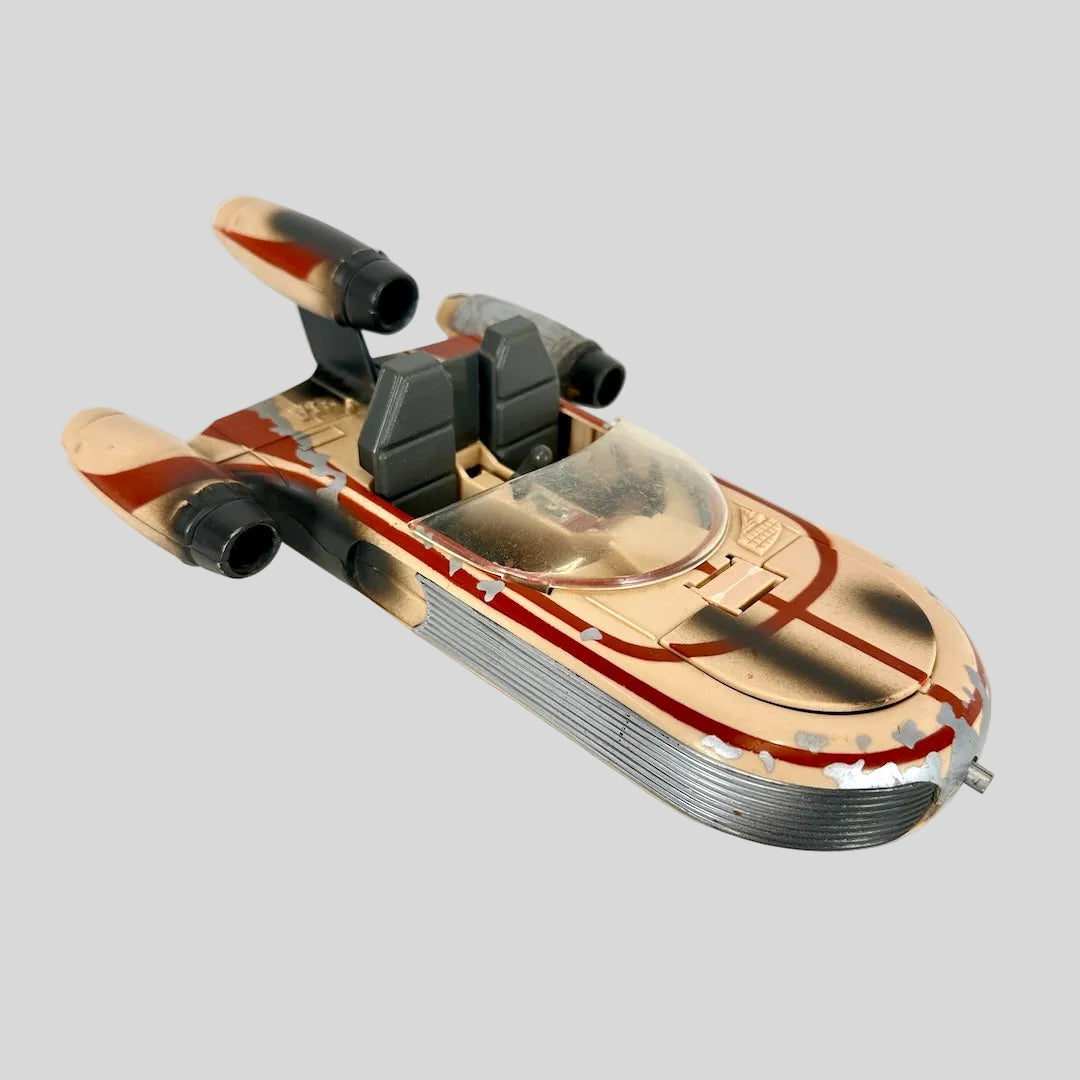 A vintage toy model of a futuristic spacecraft, featuring a weathered tan and red paint scheme.