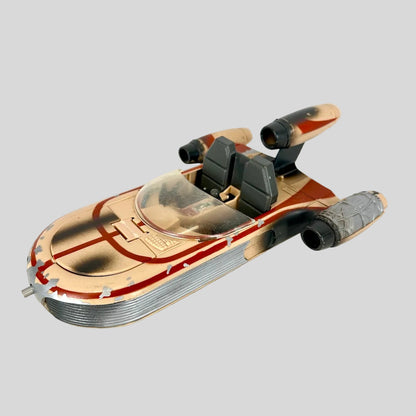 A vintage toy model of a futuristic spacecraft, featuring a weathered tan and red paint scheme.