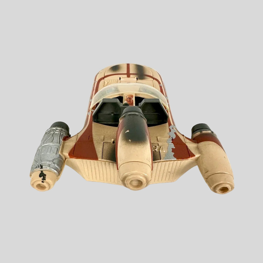 A vintage toy model of a futuristic spacecraft, featuring a weathered tan and red paint scheme.