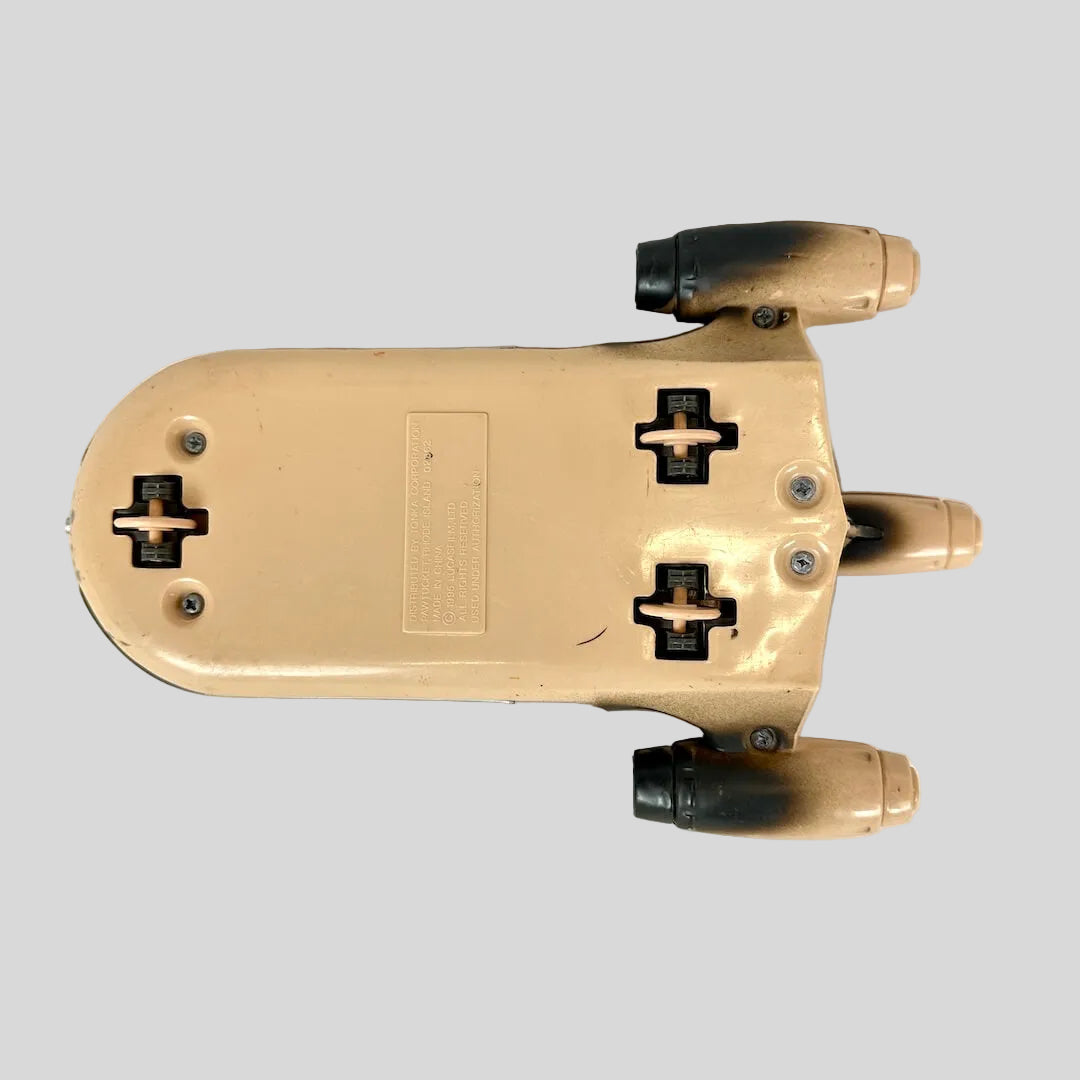 A vintage toy model of a futuristic spacecraft, featuring a weathered tan and red paint scheme.