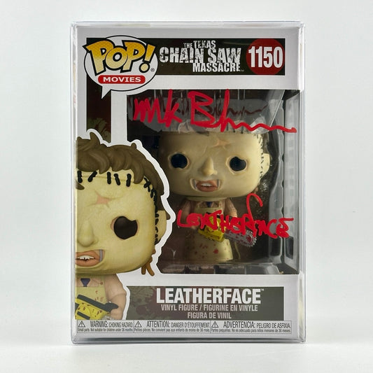 Chainsaw wielding vinyl figure still in box with red marker signature of Mark Burnham, Leatherface, across plastic window. 