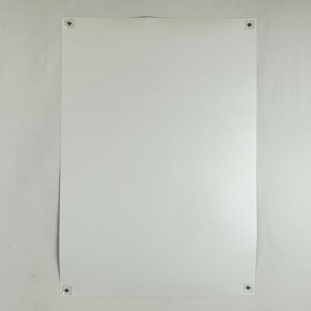 Backside of poster with no visible damage being held by magnets in each corner to a light surface. 