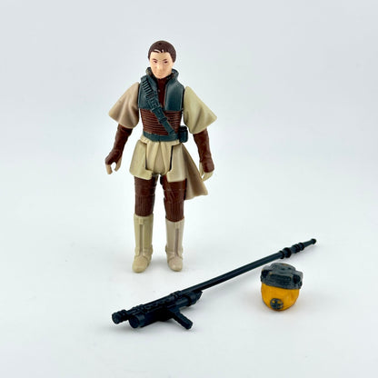 A Star Wars action figure  standing next to a black blaster and a small yellow-and-black helmet.