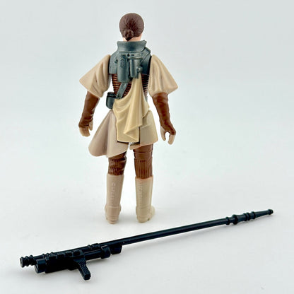 Back of action figure in brown and beige with weapon on white background. 