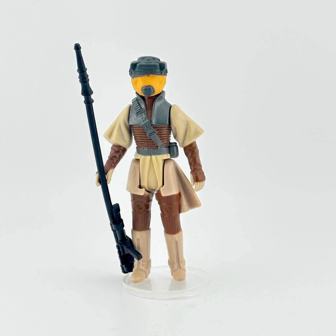 Leia action figure in tan outfit with a weapon on a white background