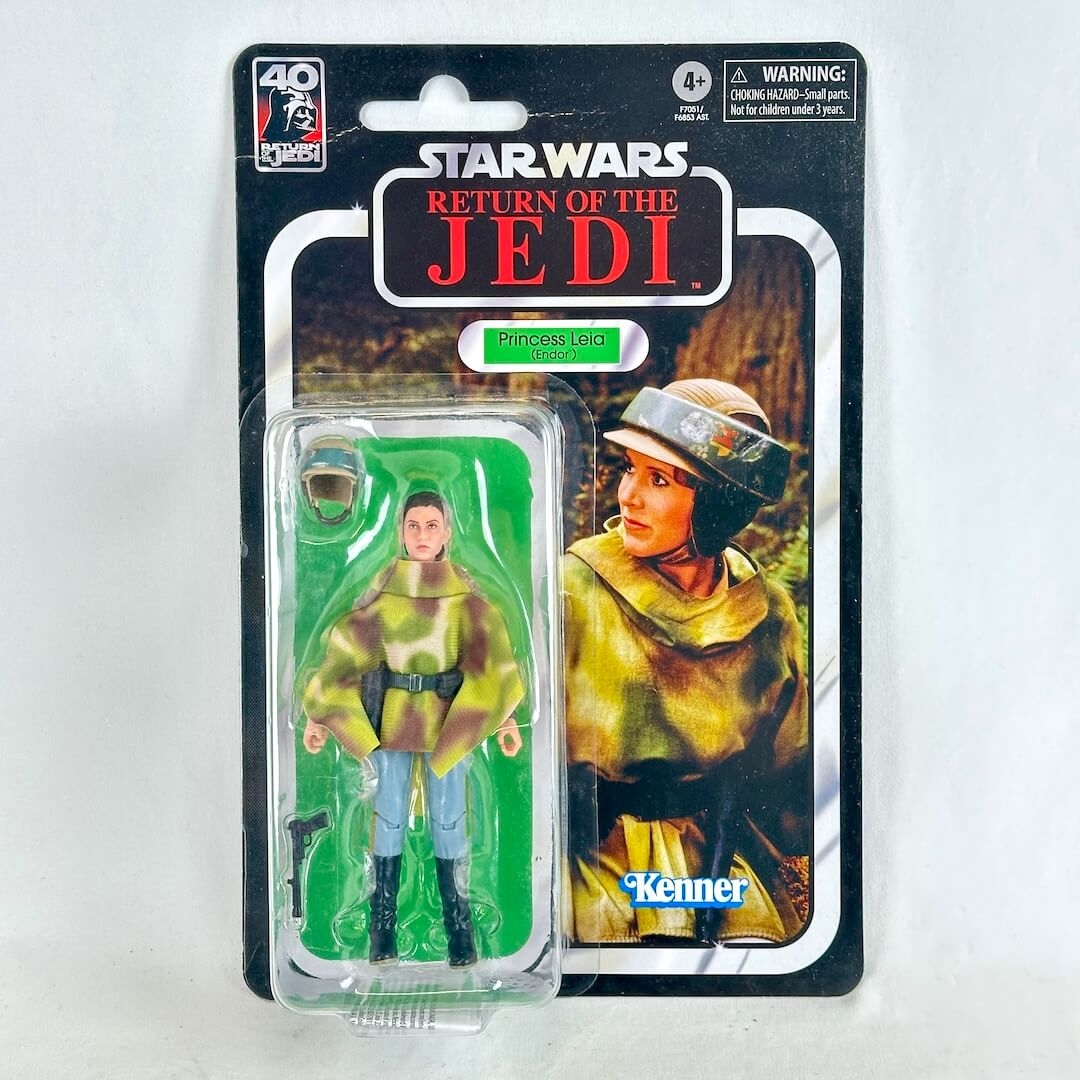 Star Wars action figure in original blister packaging with retro-style card back, figure in camouflage poncho with accessories. 