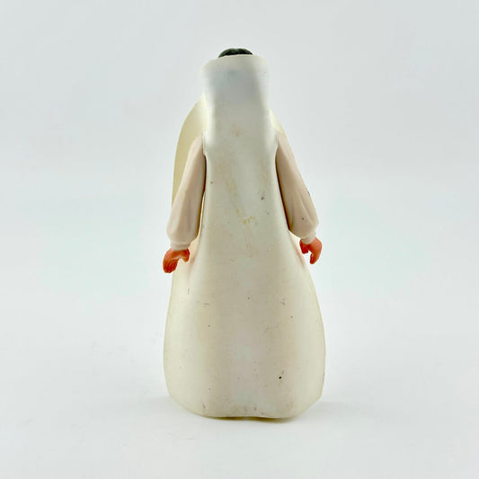 Figurine of a person wearing a white robe on a light gray background