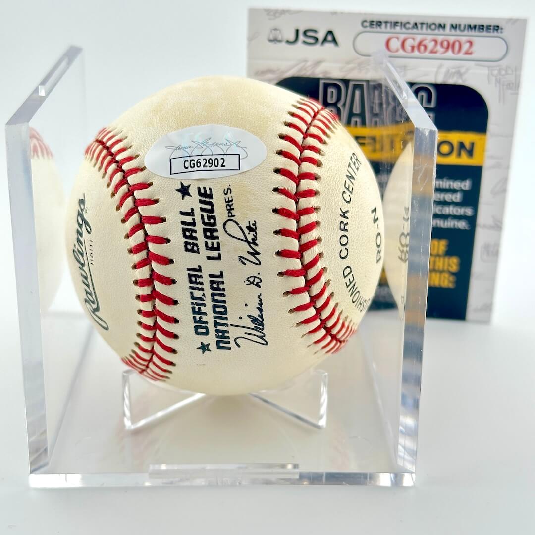 Signed baseball in clear display cube against white background with JSA certificate and sticker.