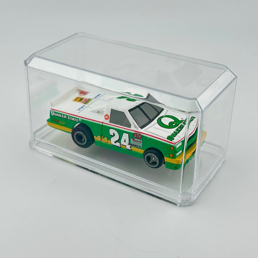 Model car with 'Quaker State' branding in a clear display case on a light gray background