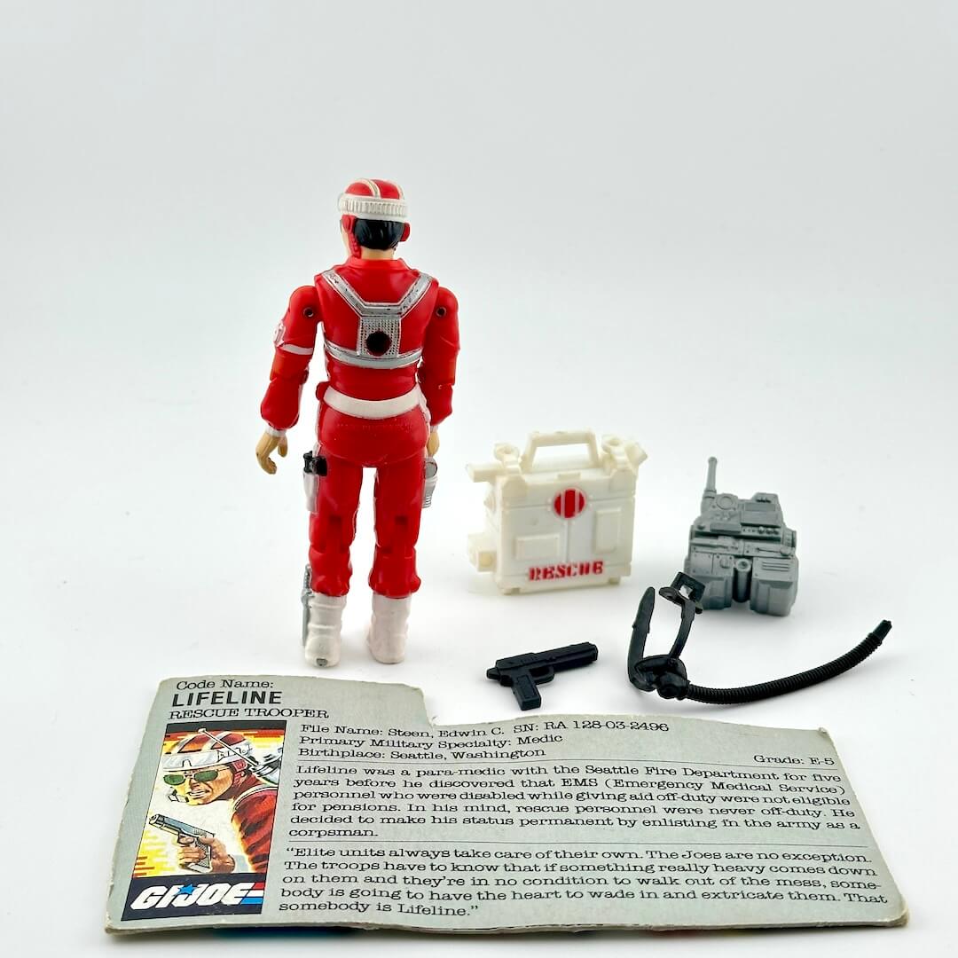 Red action figure with accessories and a card on a white background