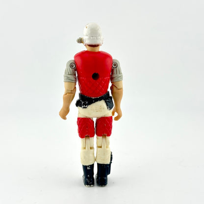 GI Joe action figure in beige pants with red vest and white helmet, photographed on white background. 