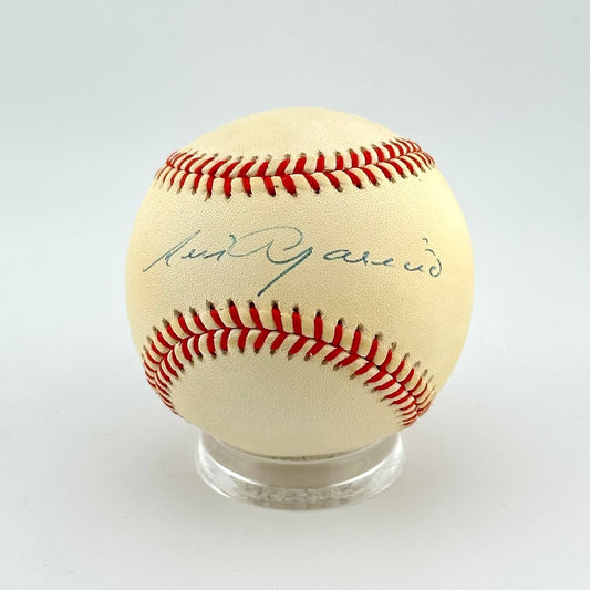 Baseball with red stitching on a clear stand against a white background