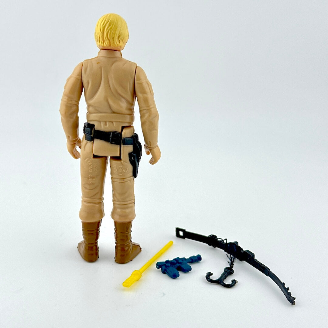 Action figure in beige outfit with accessories on a white background