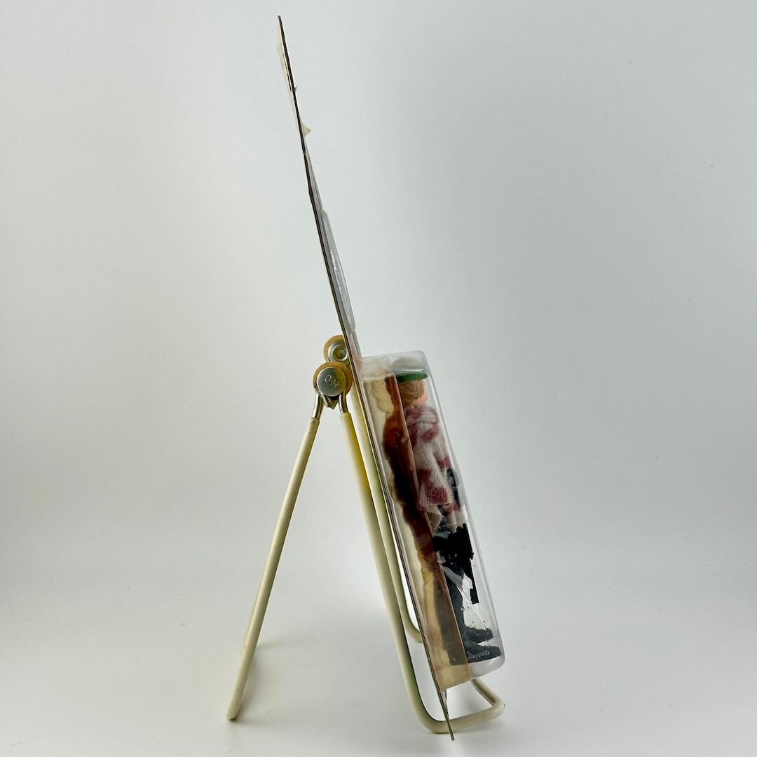 Side view of Star Wars action figure in packaging on easel against white background.