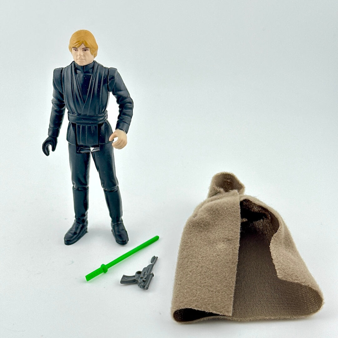 Action figure with two weapons and a cloak accessory on white background. 