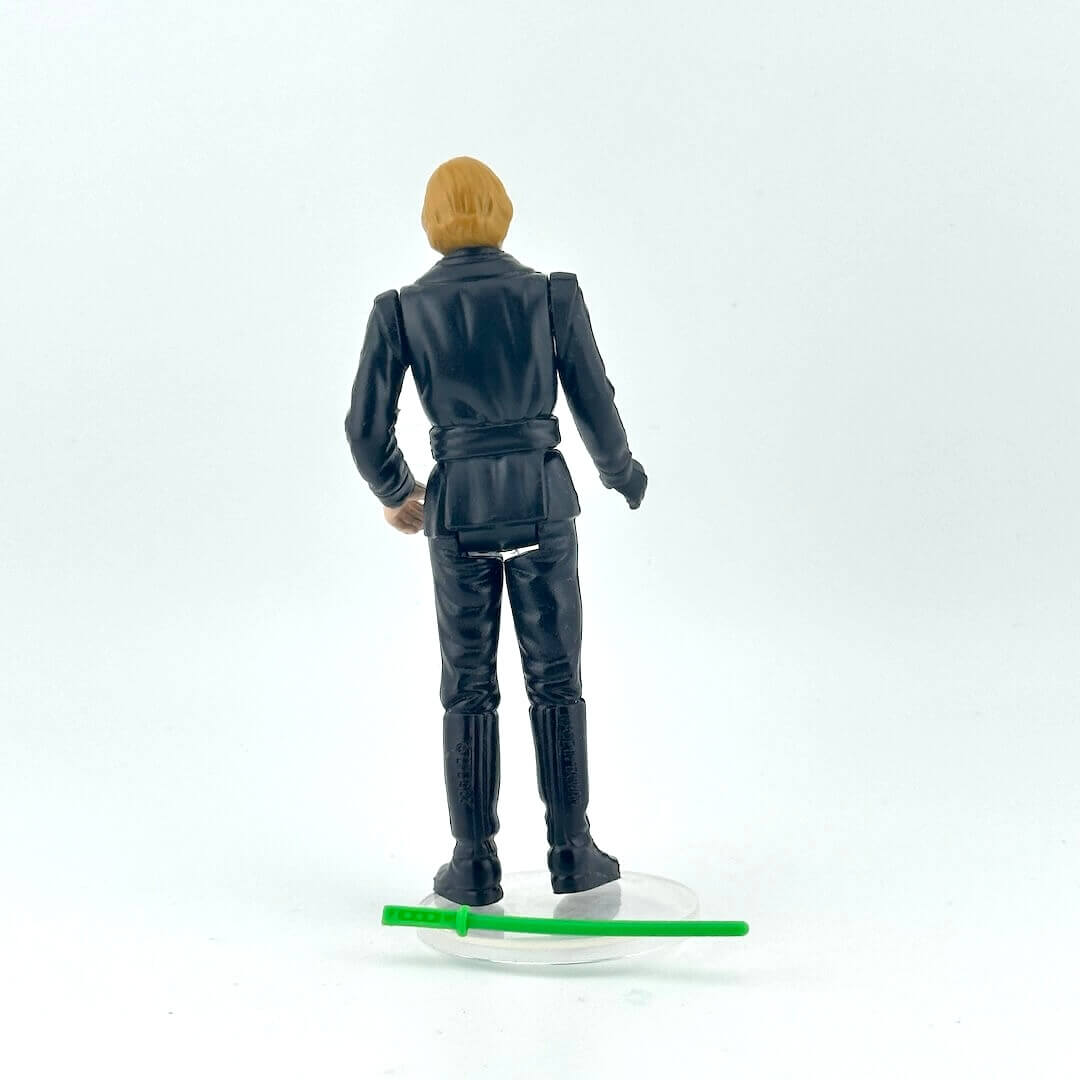 Blonde action figure in black outfit with green lightsaber against white background.