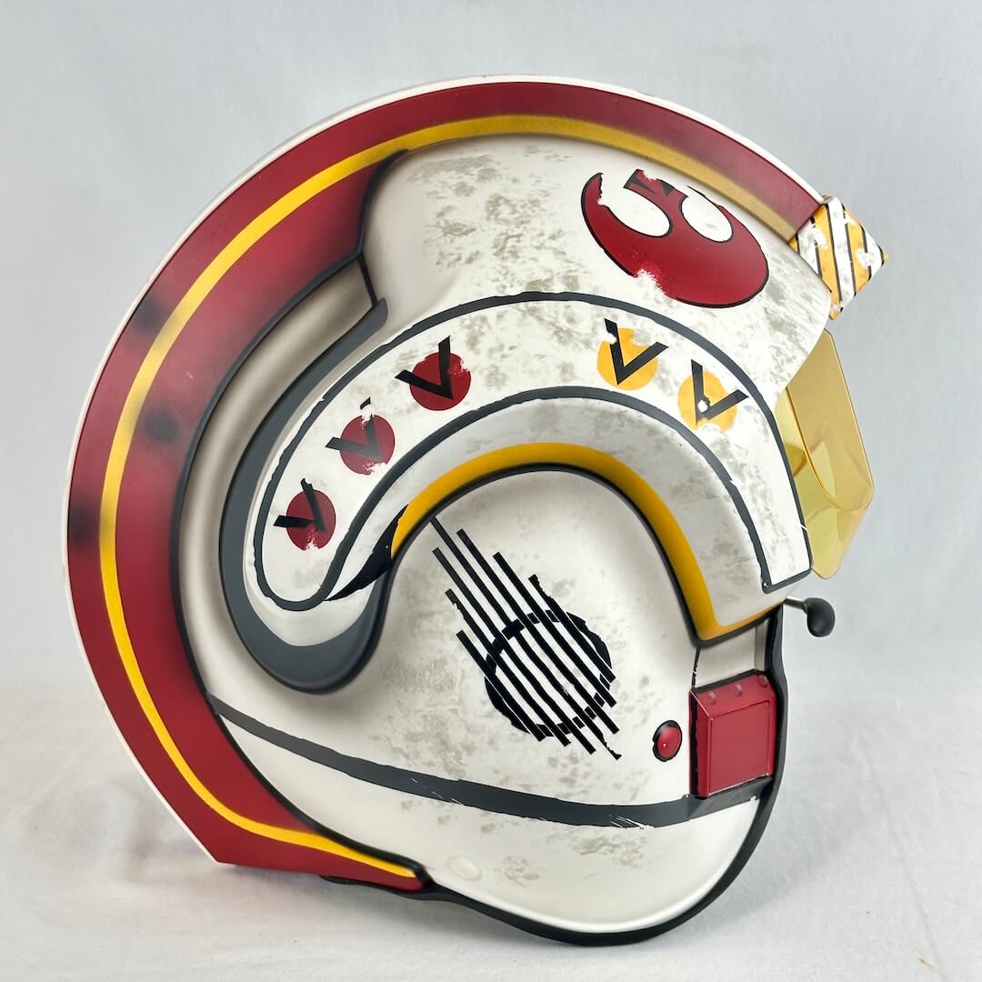 A Star Wars-themed helmet replica, featuring a distressed white base with red, yellow, and black markings.