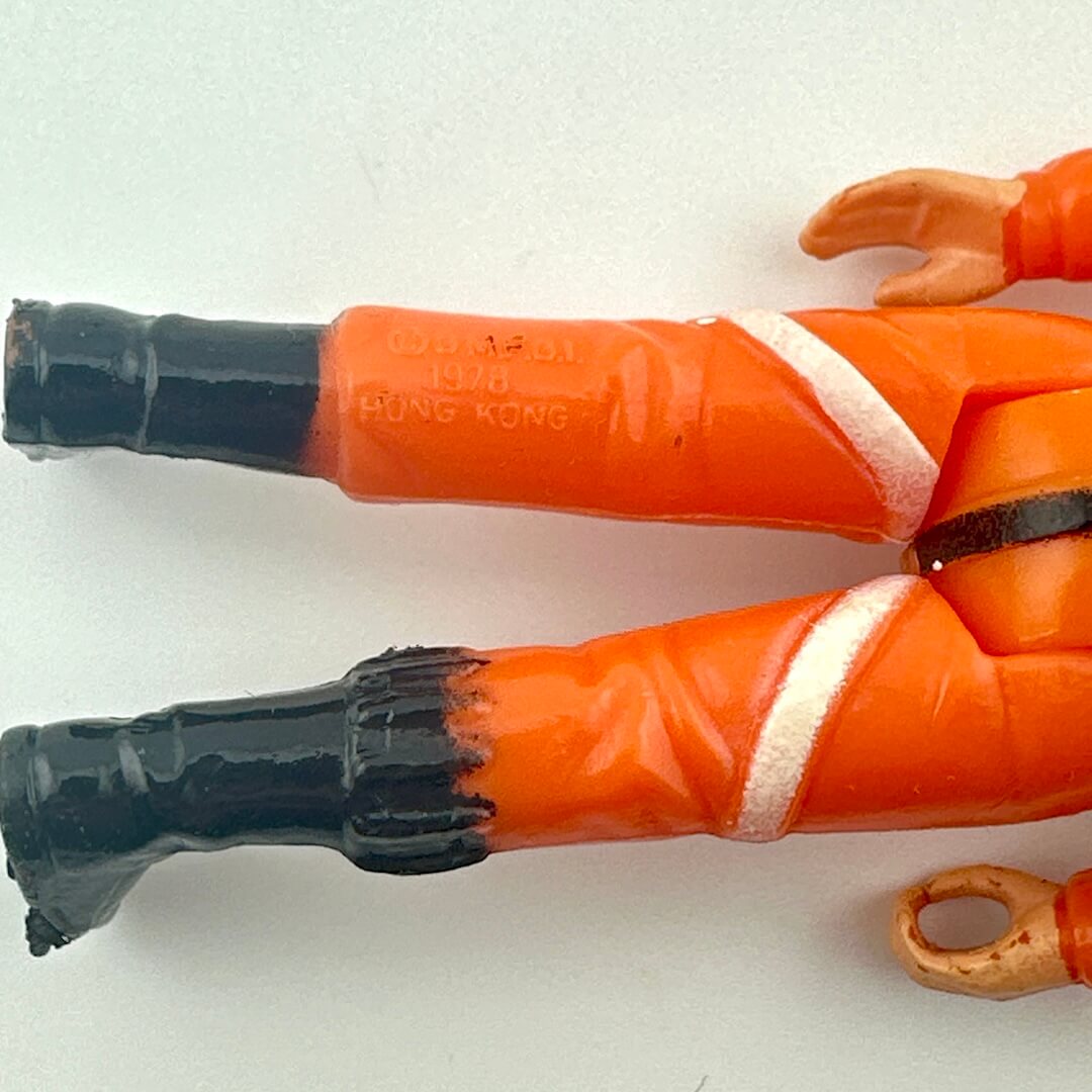 Toy figure in an orange suit with black boots on a white background