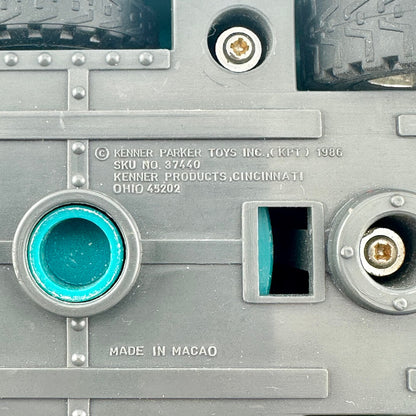 Close-up of the underside of a gray plastic toy vehicle, showing copyright and maker information embossed in plastic. 
