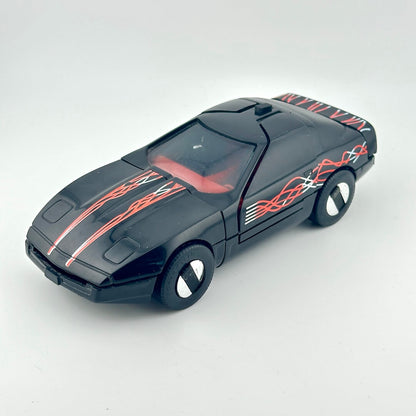 A black toy sports car with red and white flame decals, photographed on a light gray background.