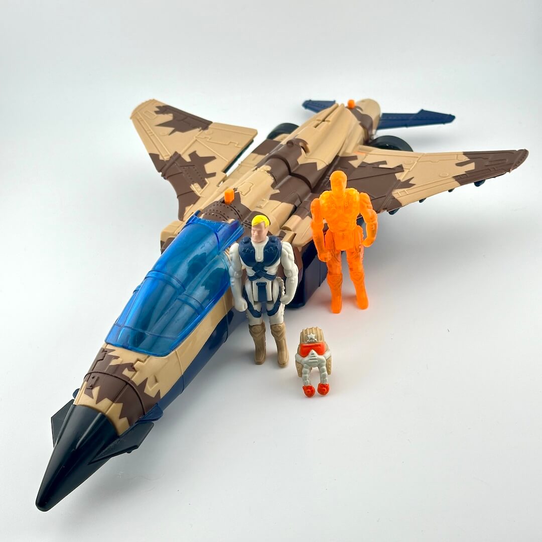A toy model of a military fighter jet in desert camouflage, accompanied by small action figures.