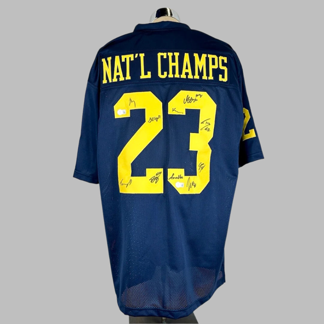 Back side of jersey showing "NAT'L CHAMPS" stitched on nameplate, over "23" signed 10 times in marker. 2 Beckett Stickers.
